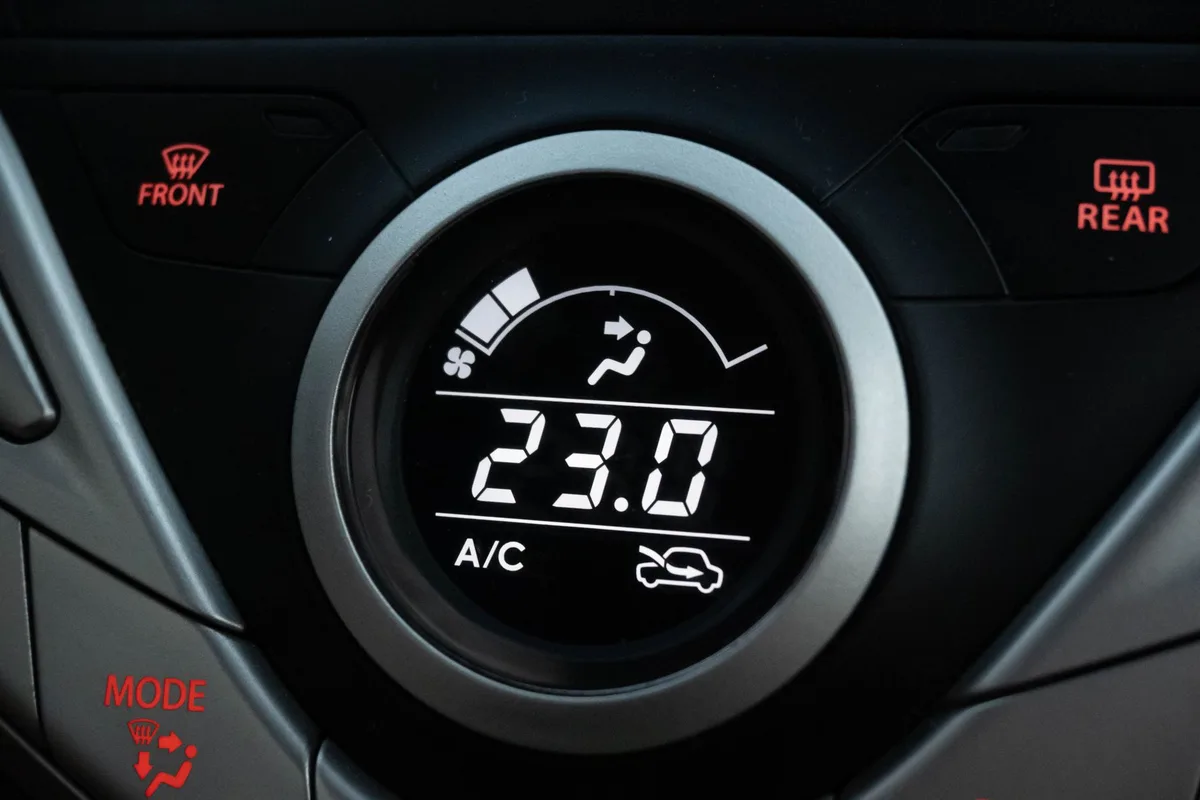 Mains réglant les commandes de climatisation du tableau de bord d'une voiture