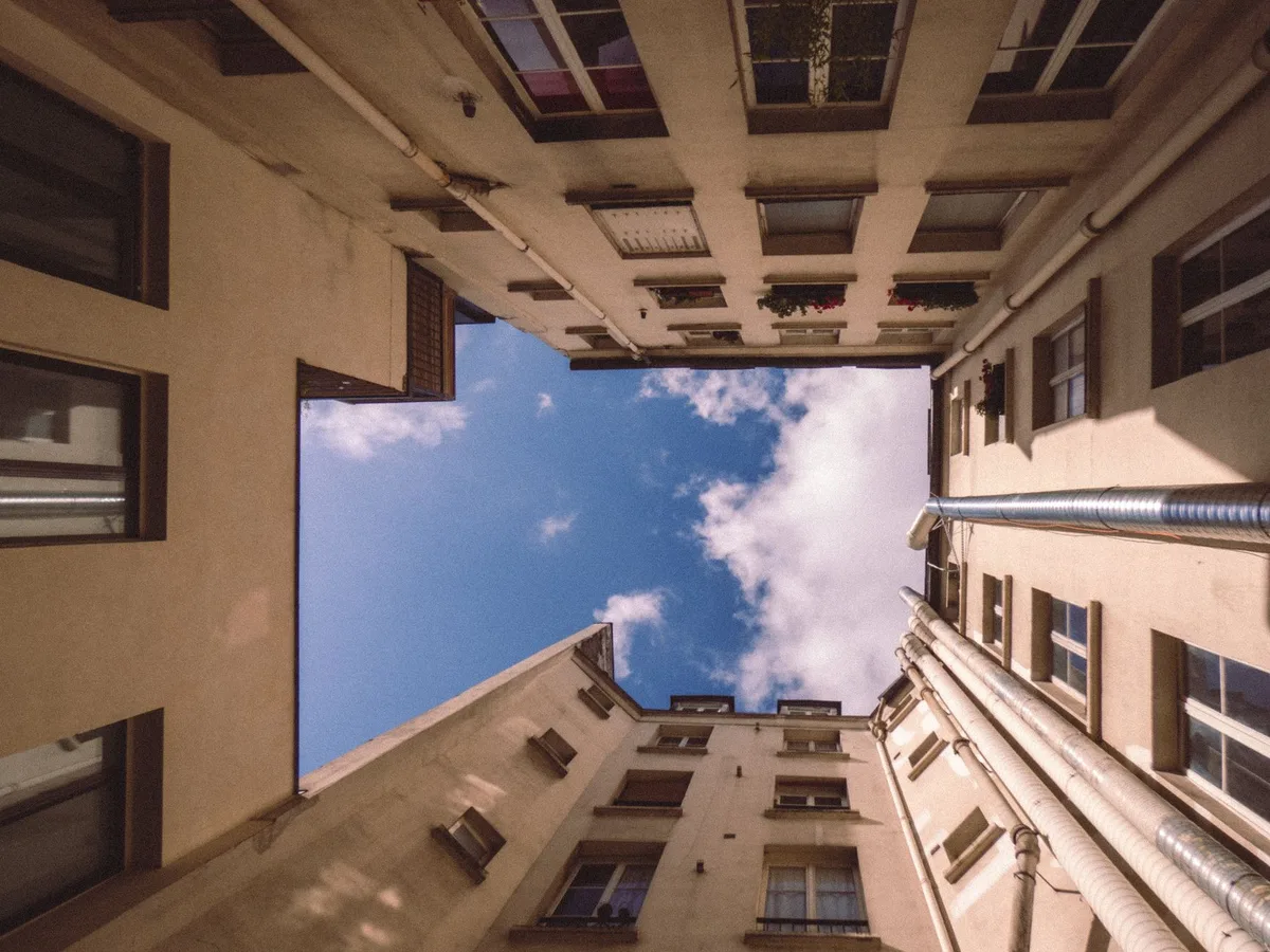 Appartement parisien lumineux avec cour pavée et jardin verdoyant visible par les portes vitrées