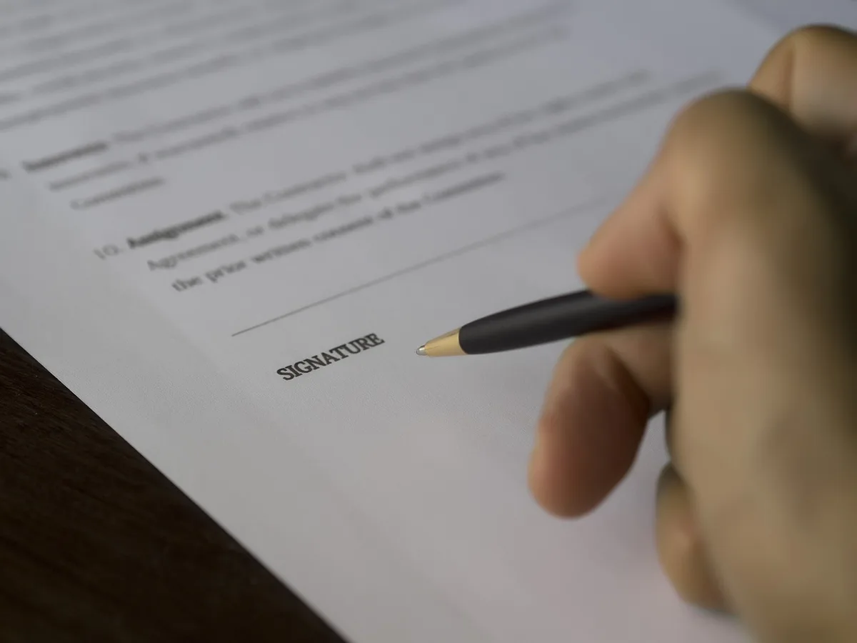 Mains tenant un contrat et des clés de voiture sur un bureau avec documents et calculatrice
