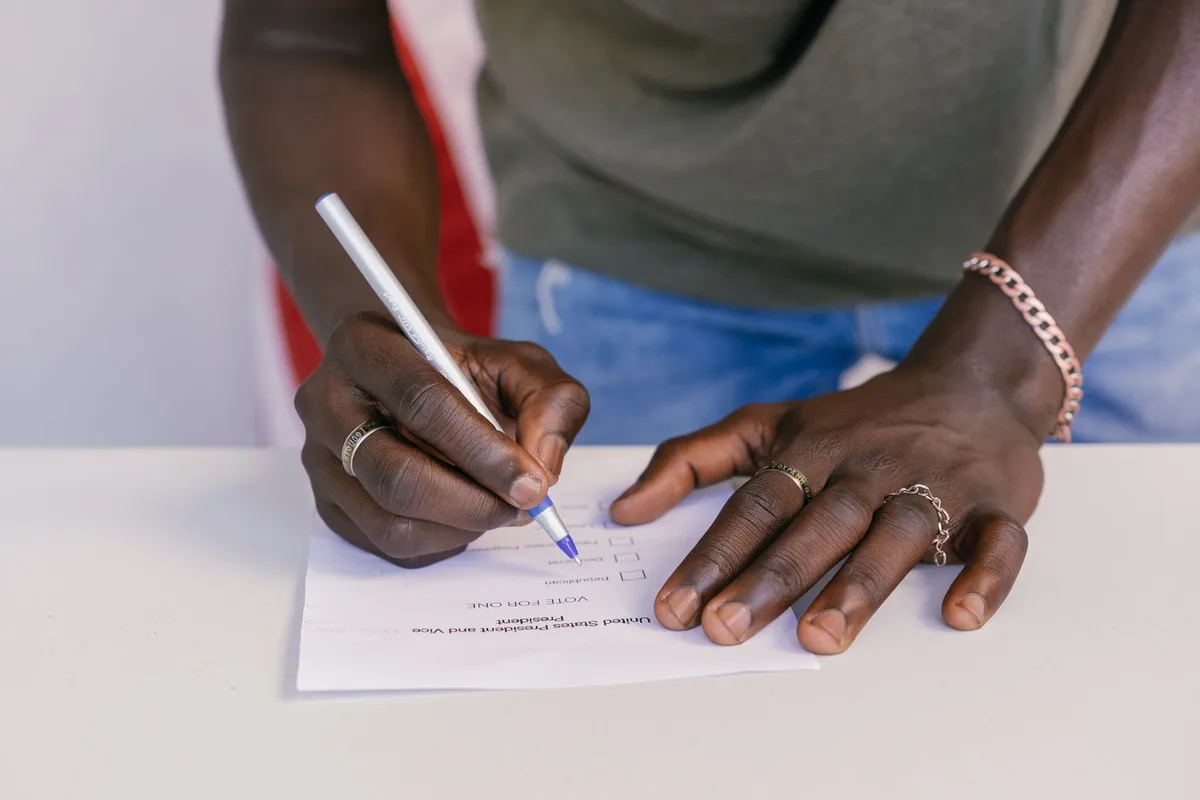 Main tenant dans une main un document cadastral avec une loupe, isoloir flou en arrière-plan