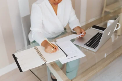 Mains examinant des documents professionnels sur un bureau avec ordinateur portable et stylo