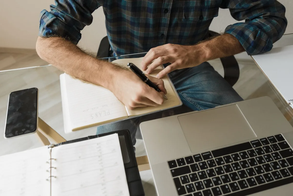 Personne travaillant sur son ordinateur portable avec un calendrier et des notes de recherche d'emploi
