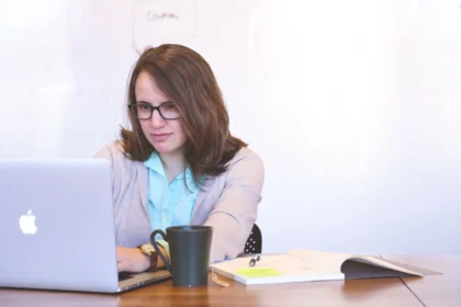 Une personne réfléchit devant son bureau avec des documents et un ordinateur pour explorer ses options de carrière.