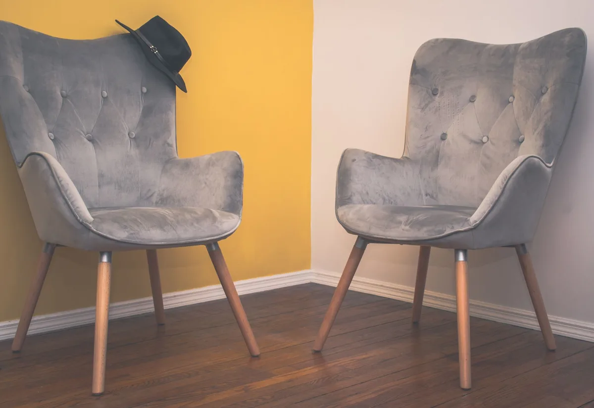 Salon chaleureux avec canapé en velours bordeaux, meuble en bois, accents métalliques et accessoires sculptés.