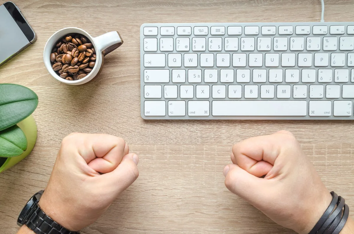 Mains tenant une lettre de rejet et un CV sur un bureau avec une tasse de café