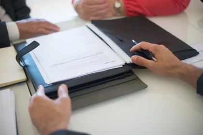 Entrepreneur examinant les documents d'achat d'un véhicule professionnel avec calculatrice et factures sur un bureau