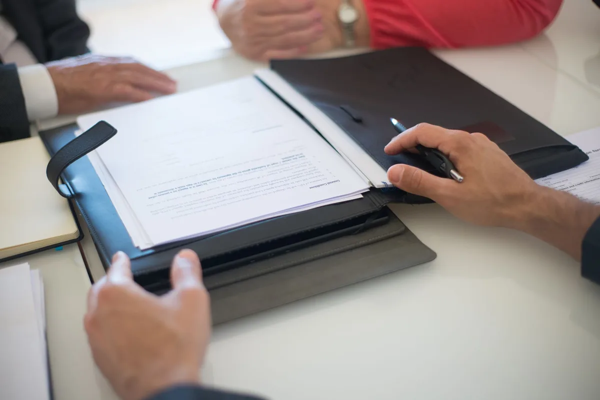 Entrepreneur examinant les documents d'achat d'un véhicule professionnel avec calculatrice et factures sur un bureau