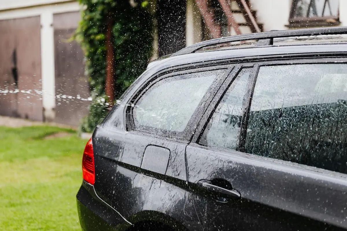 Lavage manuel d'une voiture avec un gant microfibre et un seau d'eau savonneuse