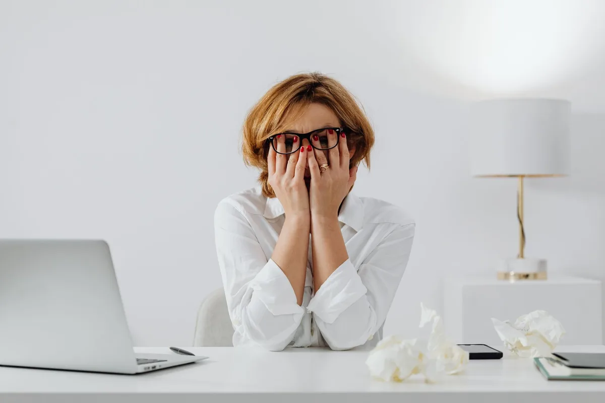 Personne assise à un bureau regardant l'heure, environnement de travail tendu