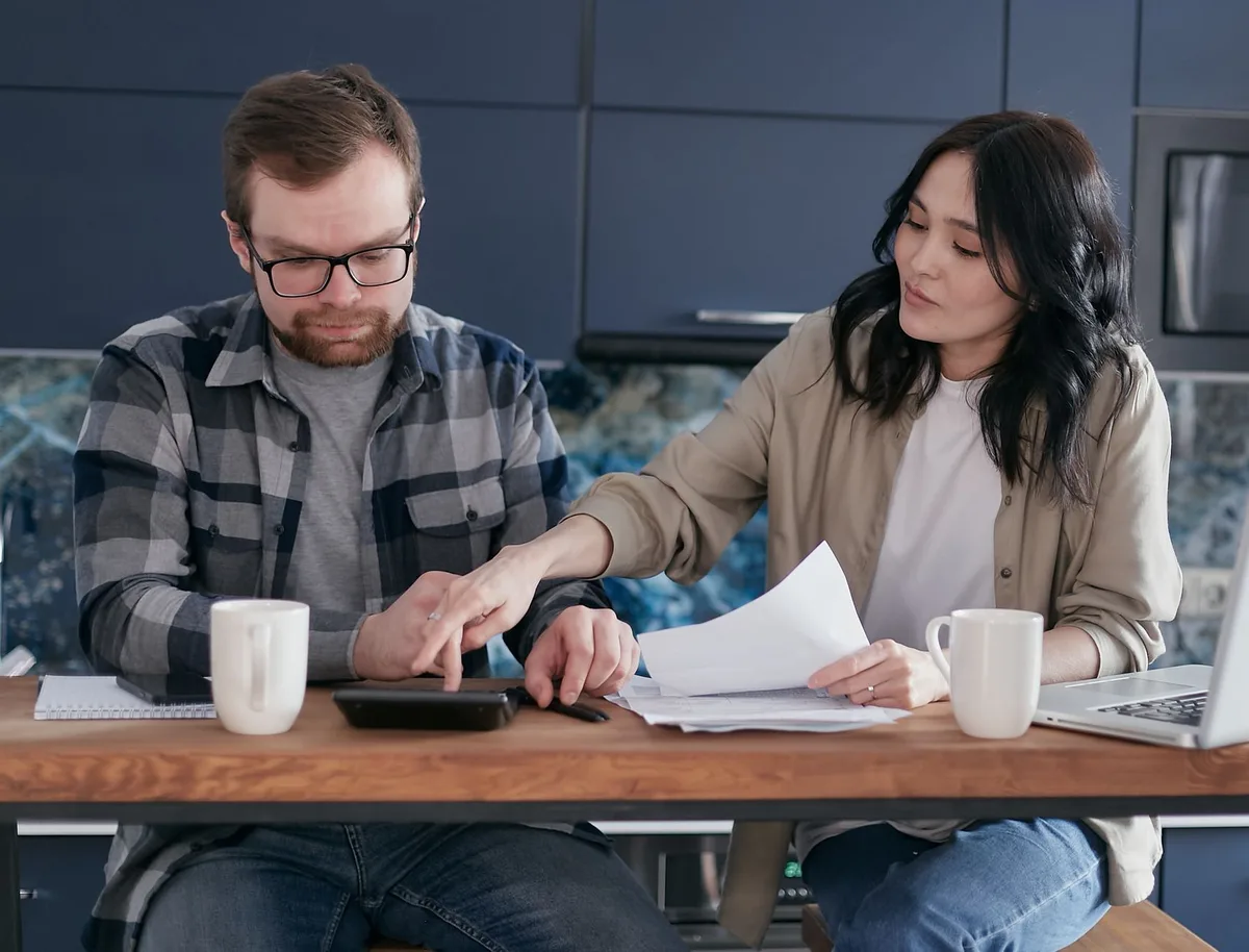 Jeunes adultes consultant des annonces immobilières et des documents financiers à un bureau