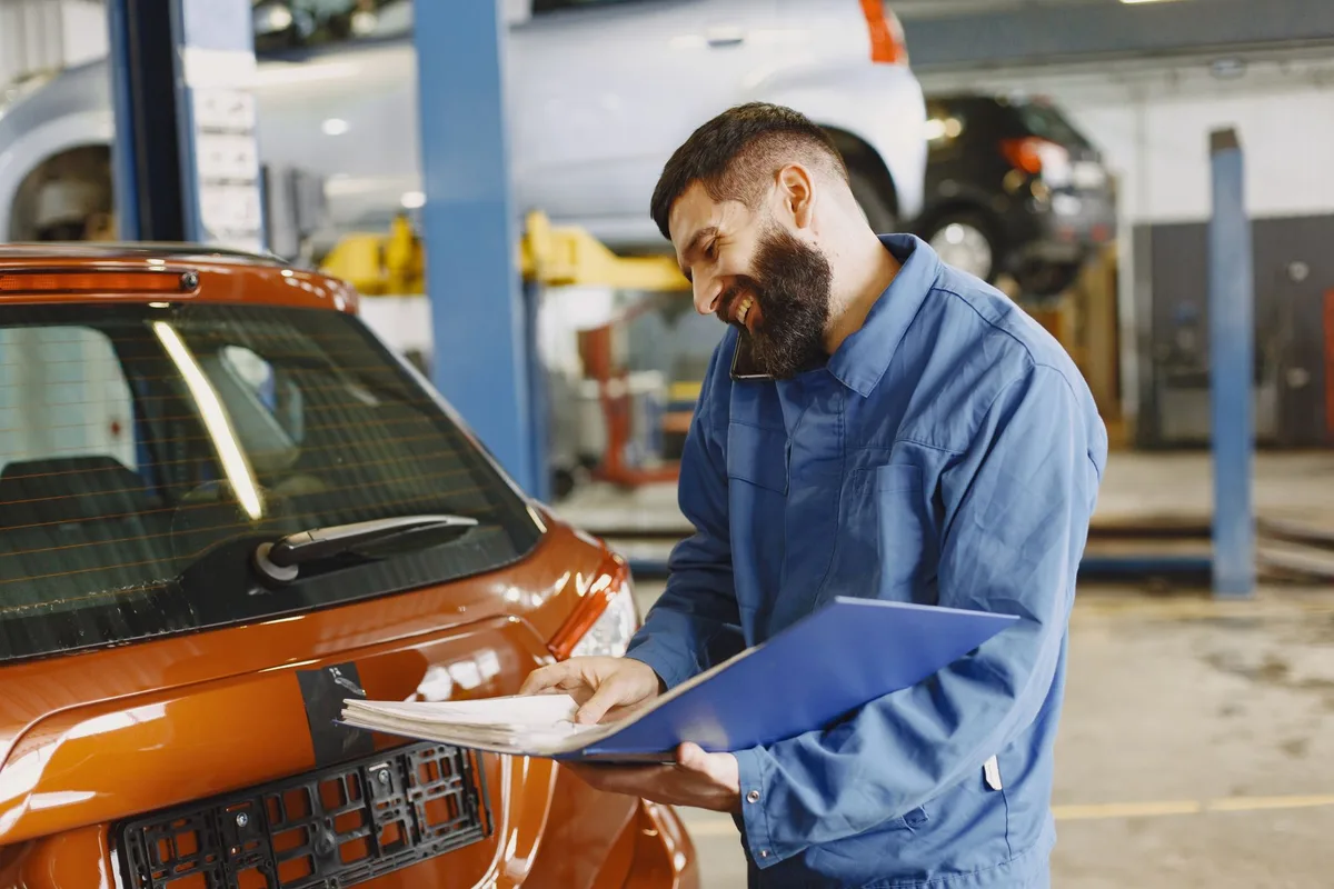 Expertise automobile : m&eacute;canicien inspectant l'&eacute;tat g&eacute;n&eacute;ral et le kilom&eacute;trage d'une voiture