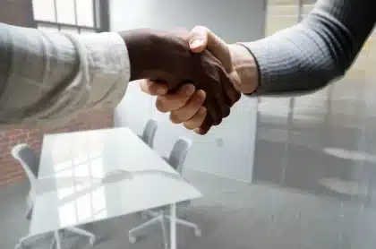 Deux professionnels se serrent la main lors d'une rencontre en bureau, l'un tenant une carte de visite