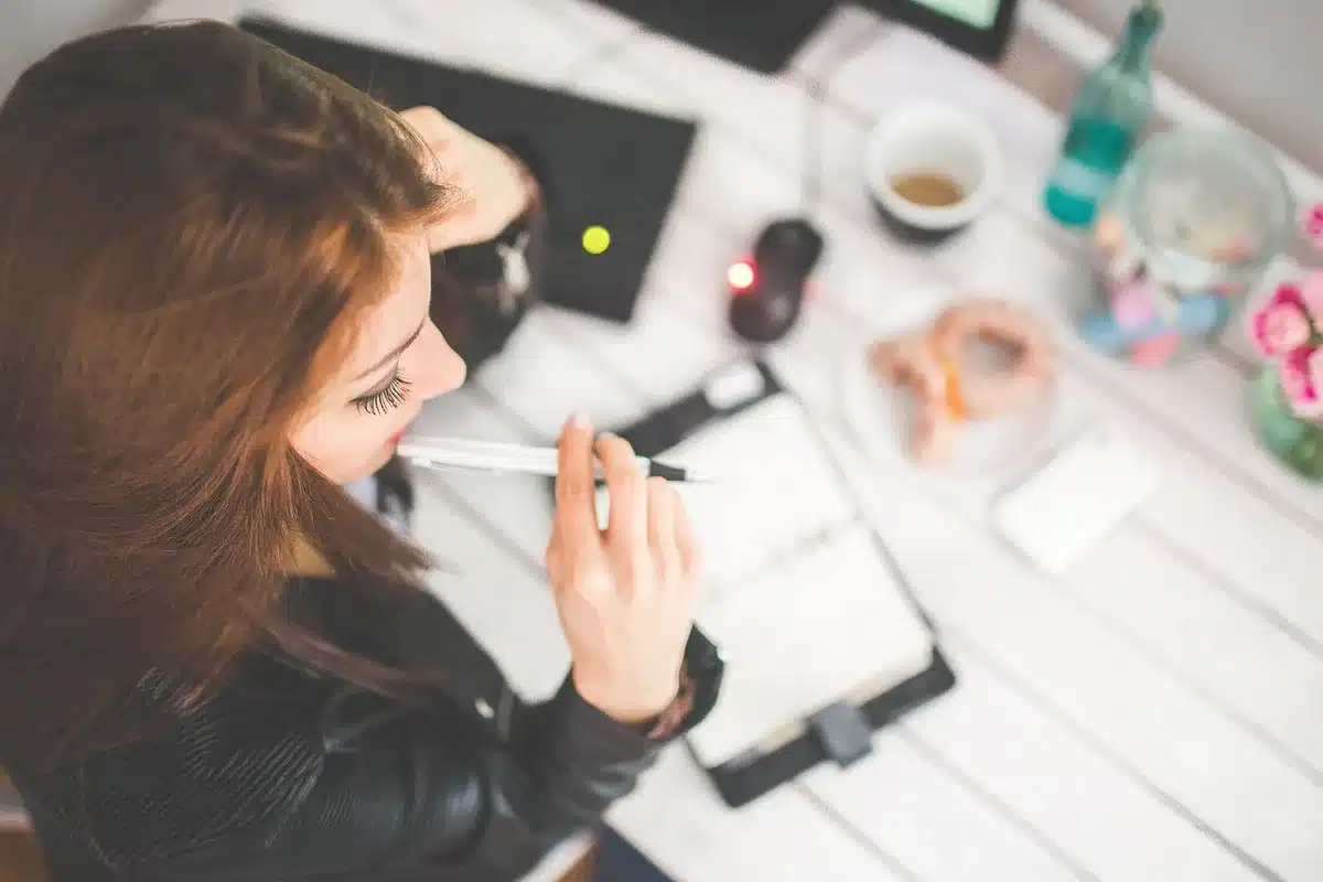 Personne r&eacute;digeant une lettre sur un bureau avec une checklist &agrave; c&ocirc;t&eacute;