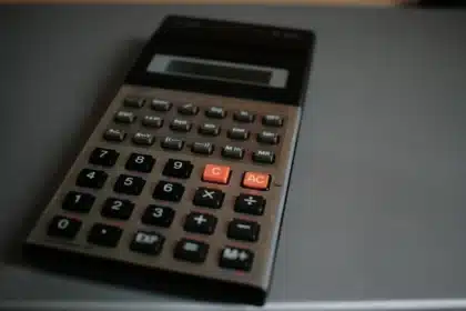 Main d'une personne ouvrant une enveloppe de facture avec calculatrice et bloc-notes sur la table