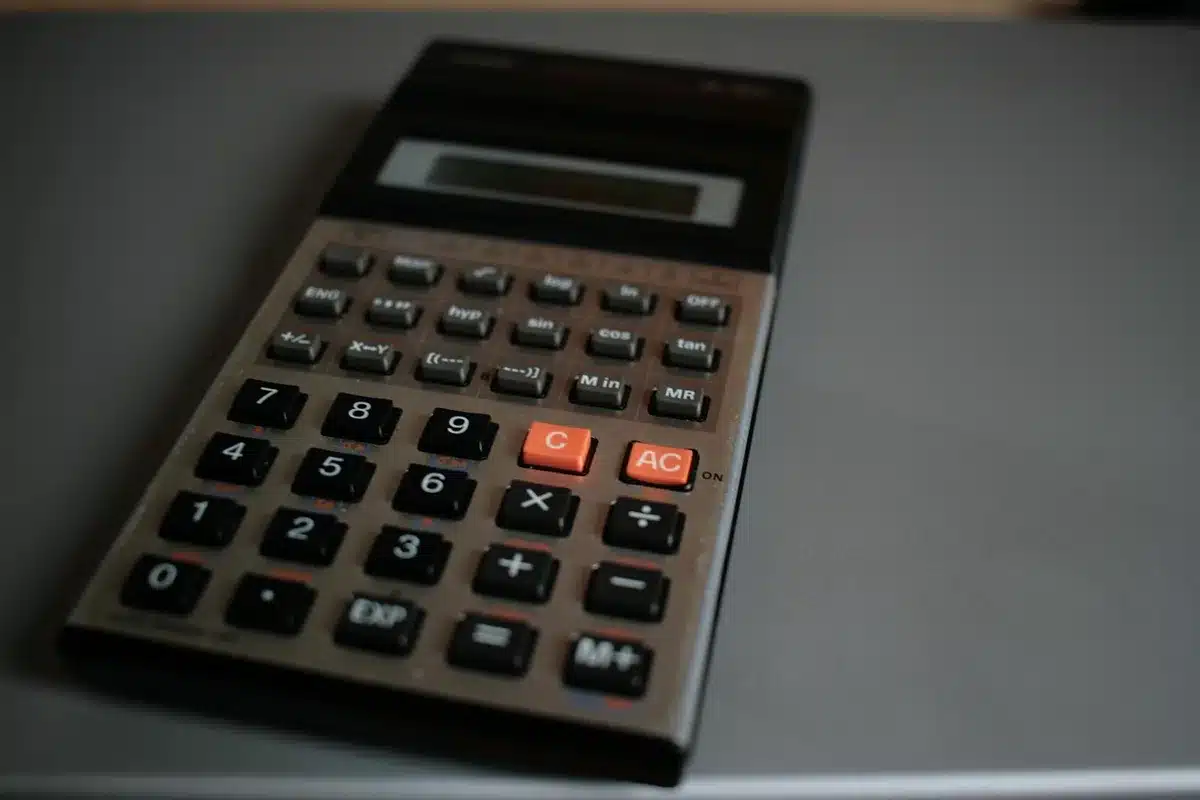 Main d'une personne ouvrant une enveloppe de facture avec calculatrice et bloc-notes sur la table
