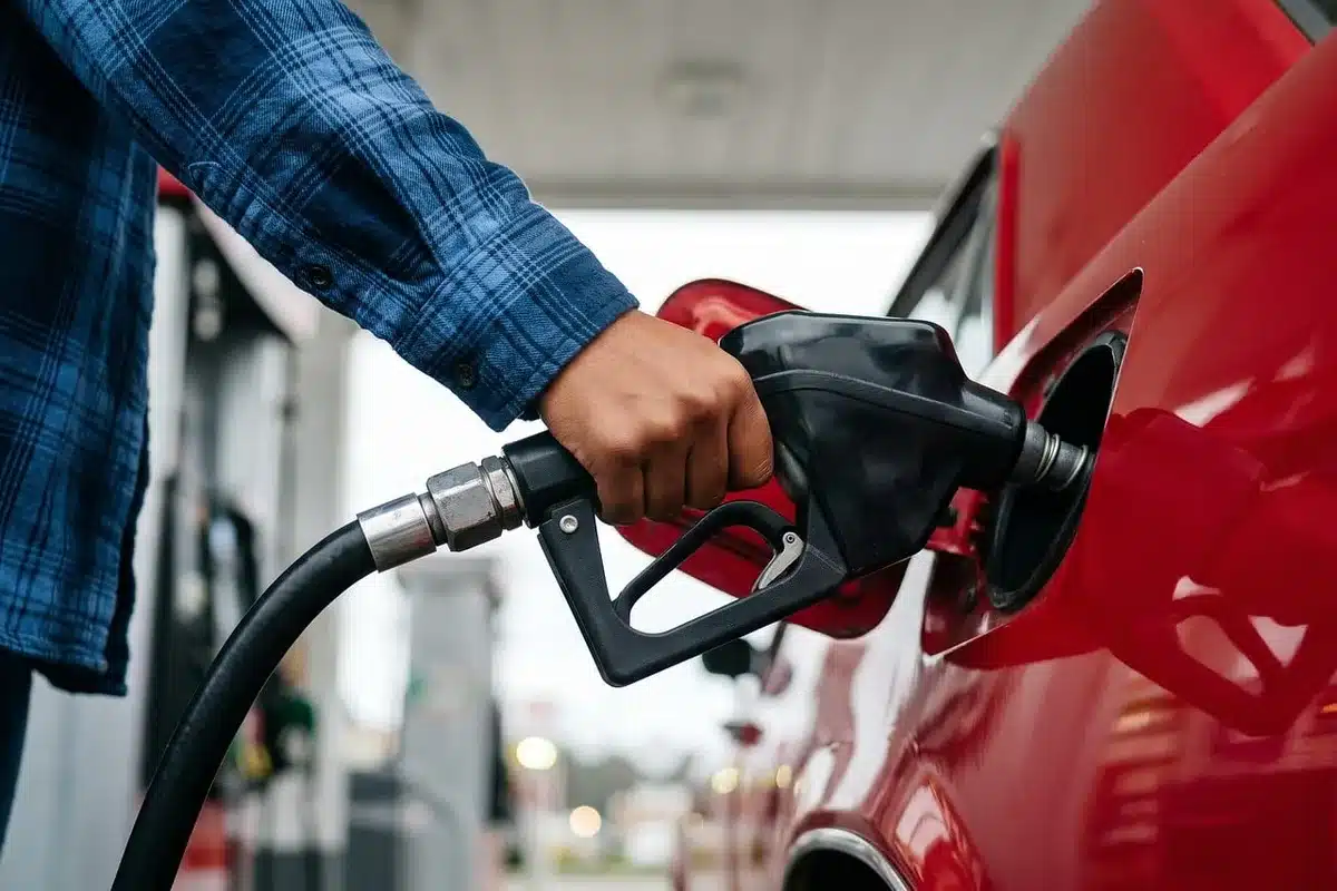 Pompe à essence avec affichage de prix changeant, main anonyme se dirigeant vers le pistolet