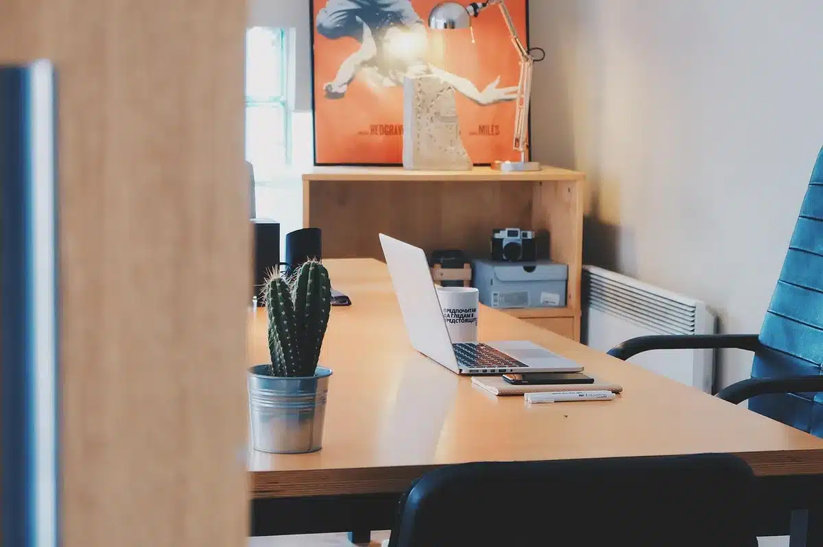 Bureau en journée avec carnet, stylo et ordinateur portable près d'une fenêtre