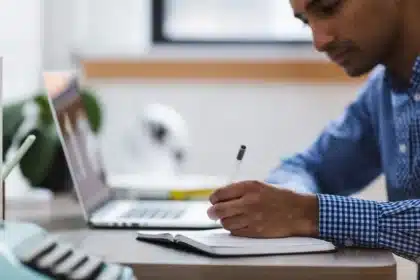Bureau en journée avec ordinateur portable, carnet et smartphone près d'une fenêtre