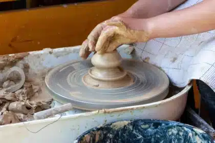 Atelier lumineux avec coquillages et mains d'artisan arrangeant une composition sur un panneau en bois