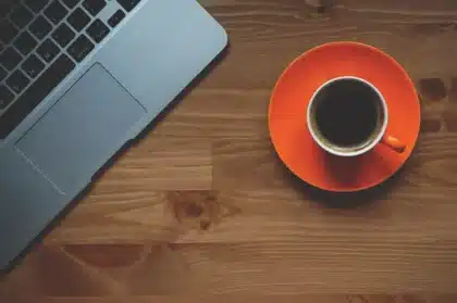Bureau en journée avec ordinateur portable, CV imprimé et mains en train de taper