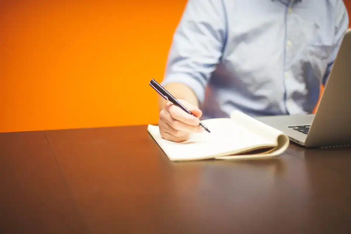 Salarié préparant ses souhaits d'évolution avec un carnet et un ordinateur