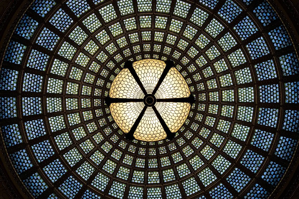 Feuillages métalliques surdimensionnés et fleurs en verre soufflé dans un intérieur lumineux