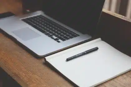 Un ordinateur portable et des notes de formation sur une table de bureau éclairée par la lumière du jour